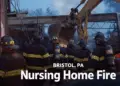 Firefighters and an excavator working at the scene of the Bristol, PA nursing home fire after the December 2025 explosion.