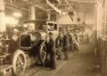 Historic Ford Motor Company assembly line showing workers assembling early automobiles during the rise of modern manufacturing in Dearborn, Michigan.