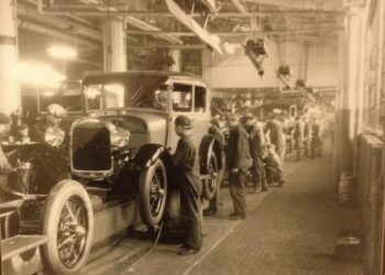 Historic Ford Motor Company assembly line showing workers assembling early automobiles during the rise of modern manufacturing in Dearborn, Michigan.
