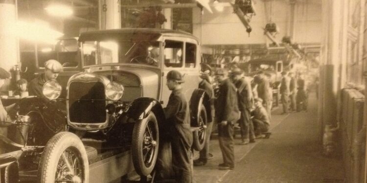 Historic Ford Motor Company assembly line showing workers assembling early automobiles during the rise of modern manufacturing in Dearborn, Michigan.